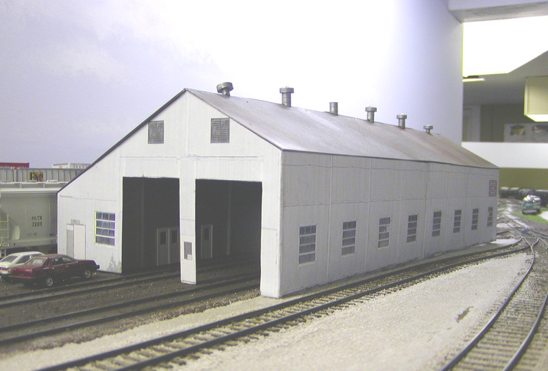 Looking northwest.  Basic interior work (walls, bracing, and doors) has been completed, but I still need to add a cement floor and numerous details.  The first interior door leads into the yard office.  A lot of railfanning trips started with a visit to that office. :-)