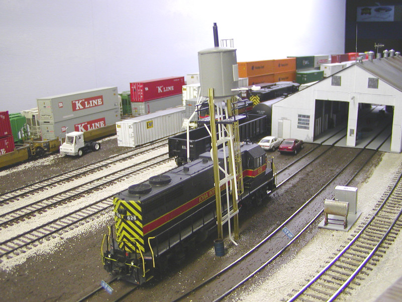 Model view of the west sand tower and fuel pad.  I just ordered the fuel crane, so I hope to weather and complete the pad later this week, as well as painting and weathering the sand tower.  Exterior lights have been added between the engine bay doors on both ends, taken from a JTT streetlight/stoplight set, as was the light on the sand tower.

The sand tower was scratchbuilt using Evergreen styrene shapes, Special Shapes brass I-beam, a Bar Mills #2003 horizontal fuel tank, and Central Valley fencing for the wood platform beneath the tank.  The fittings and nozzles on the sand pipes are surplus from Cannon EMD fuel tank detail sets, and the etched caged ladder is from Walthers.