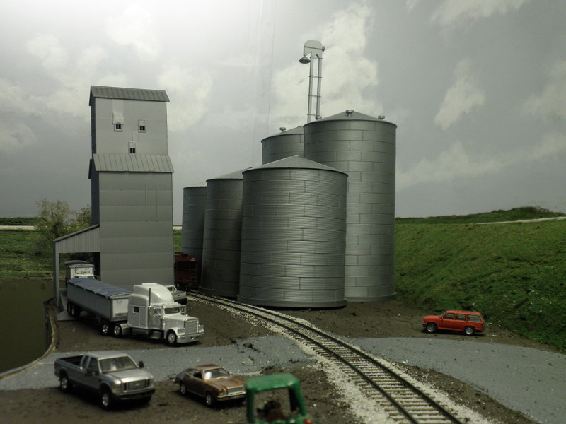 Looking north at new Hancock Elevator arrangement.  Bins closest to the spur used to be on the aisle side of the original elevator structure, but were increased in height and moved to the back to allow the benchwork to be skinnied down.  Hillside on the right was cut back, and taller bins were moved back further to accommodate the new arrangement.  The entire structure was painted with Rustoleum Flat Aluminum.

The more I look at this photo, the more I realize I need to excavate more of the hillside so I can spread the grain bins out more, better matching the prototype's footprint.