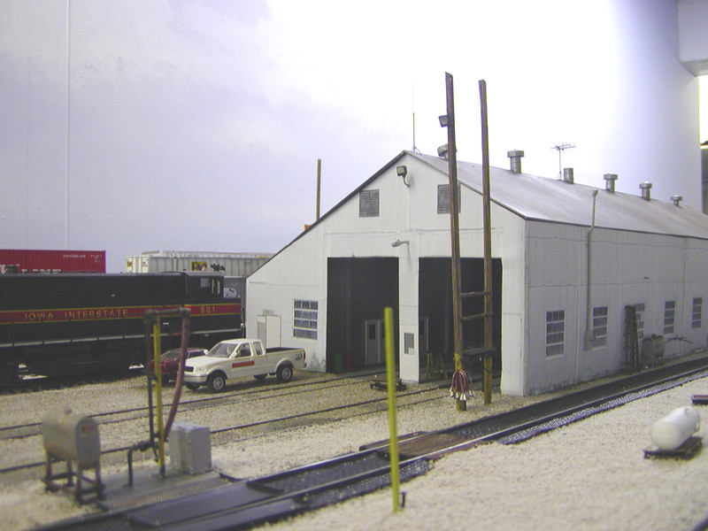 Looking NW at the new shop flood lights, electrical meter and conduit, and gas line stub (protected by the yellow section of rail planted in the foreground).