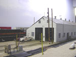 Looking NW at the new shop flood lights, electrical meter and conduit, and gas line stub (protected by the yellow section of rail planted in the foreground).