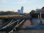 Looking south along BN's Pacific Jct. line.  In the foreground is the switch to the Bayard line; the IAIS switchmen are riding the point on a stack car shove eastward on their main line, and an inbound KCS grain train waits in the background.