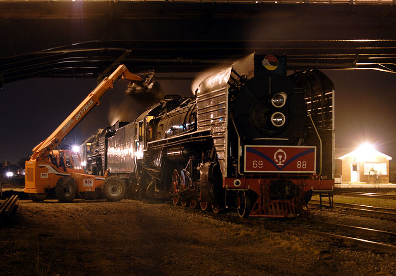 Now that the triple-header is coupled to the train under the Centennial Bridge in Rock Island, IL, the steam crew adds another bucket load of coal to the 6988.