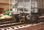 Due to the grade of the Hancock spur and pocket track as they decend from the mainline, I had to create a braking system to allow cars to be tied down on these tracks as they are on the prototype.  What I ended up using was a piece of piano wire attached to the end of a wood dowel that extends through the front fascia of the layout.  The wire passes up through the roadbed at an angle, so when the control rod dowel is pressed in, the wire projects upward.

I drilled the hole through the roadbed large enough that the piano wire would fall back into the hole when not held in the engaged position, bending the tip of the wire to prevent it from falling all the way through the hole. In order to engage the brake, the operator has to press the activation rod until the weight of the cars against the extended piano wire will hold it in place. Once the cars are pulled away from the wire, gravity causes it to fall back in the hole, disengaging the brake automatically.

I liked this approach since it saves crews from having to remember to disengage the brake and potentially derailing on it later.