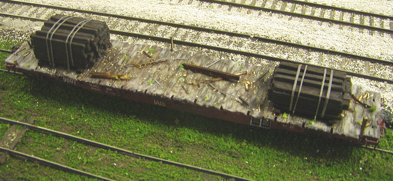 Here's an overhead view of my second attempt at weathering 9007's deck.  I used a wire brush attachment on my Dremel tool in order to give the plastic deck a more worn look, which had the added benefit of exposing the light grey P2K deck underneath the Bragdon weathering powders.  Among the clutter I added were ME ties (whole, as well as shavings), ME rail, strips of Chart-Pak tape (painted a mix of rust and bare steel colors to represent steel banding of various ages), some ballast, and a few weeds made from ground foam.