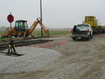 A backhoe buries the south rail in the road crossing, awaiting later installation.