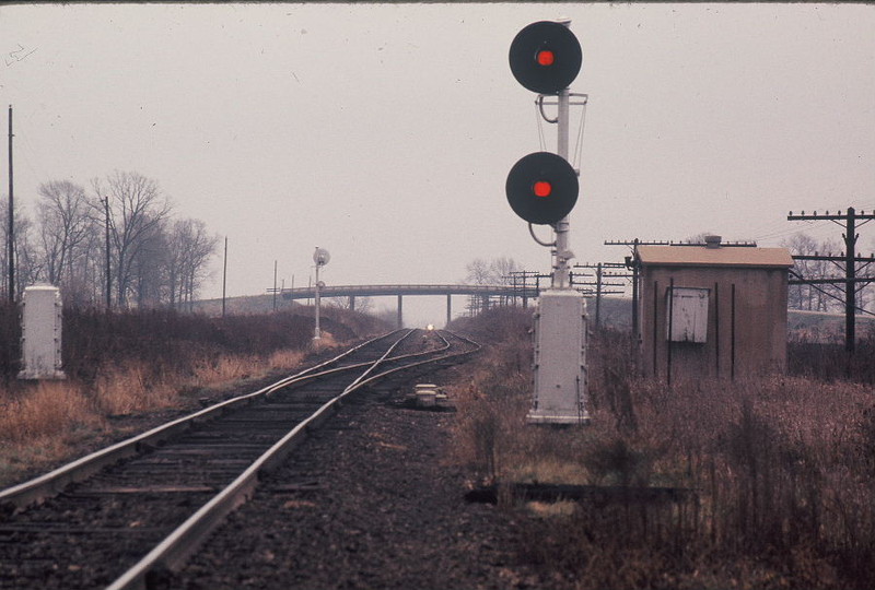 Looking east at the west end of West Lib. siding in CTC days, November 24, 1973.  The cement relay hut is still there today, pushed off into the ditch at approximately the same location as what is now the west switch of the ECI ramp.  At one time double track extended all the way to the Iowa River bridge in Iowa City; in the 1950s the eastbound main was removed up to this point.  Later still the diamond in front of the West Lib. depot was single tracked, making this a siding; the east switch was immediately west of the diamond directly in front of the WL depot.