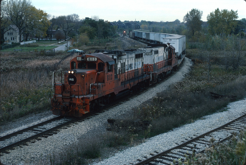 Outbound road freight is climbing track 9; Evans yard lead is visible going through the fence gate in the background.  This view is not possible today due to rampant uncontrolled brush growth.