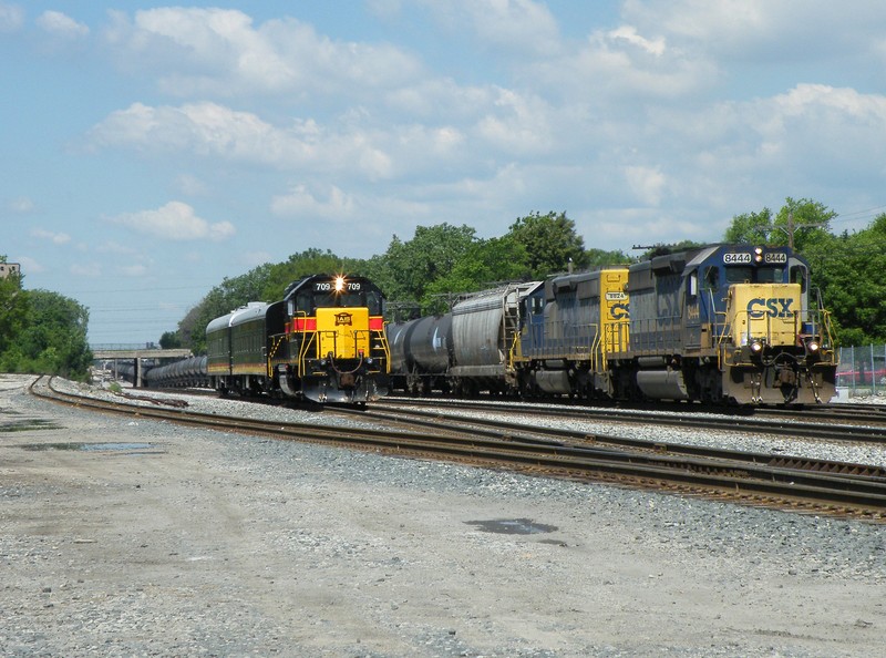 A CSX ethanol train departs Riverdale Yd for points east while IAIS Business train with CF&E crew X540 holds for two on the Harbor...