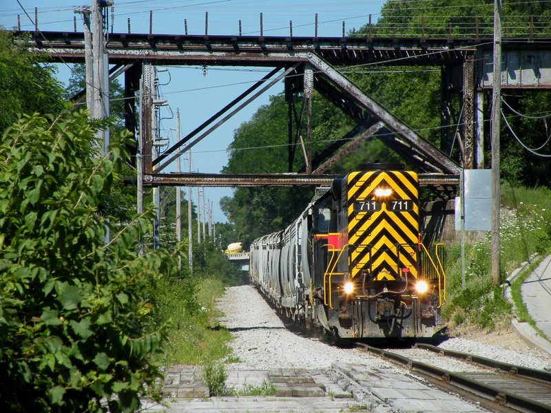 Now heading east, Iowa 711 ducks under the old Gruber Line bridge structure, spanning the entire valley. Iowa 720 hitches a ride on the rear, making it easier to conduct their switching duties at Utica.