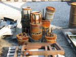 Here are a couple EMD 645 power assemblies.  The rusty silver cans sitting on top are pistons; two cylinder heads are laying on the ground on each side, with 4 exhaust valves per head.  Visible on the cylinder liners is the row of air inlet ports; when the piston reaches the lower end of its stroke these ports are uncovered while simultaneouly the exhaust valves open.  Pressurized air from the blower/turbocharger then rushes into the cylinder through these ports, giving a fresh charge of air while also pushing the exhaust gases out through the valves.  As the piston comes back up it covers the ports again, the exhaust valves shut, and the air is then compressed by the piston.  At or near top dead center the injector (not visible, but it goes in the middle of the head) will inject a measured amount of fuel, and the heat from compression will ignite the fuel, beginning the power stroke.