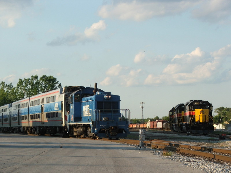 Metra's little SW1 #1 assigned to Blue Island shoves 4 high liners down the runner toward their shops for wheel turning. IAIS 702 is beginning to pull down the yard lead in preparation for the signal out of town. 05-31-08.