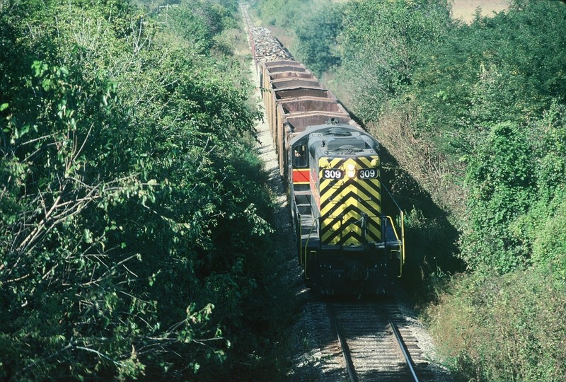 309 on a work train, running long hood forward head east from Iowa City under American Legion Road in late October 1990.